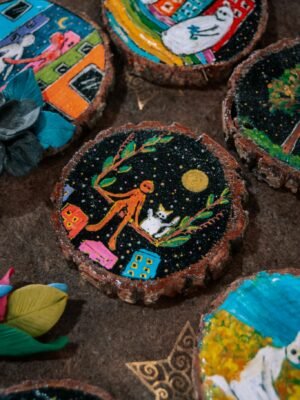 Unique handmade wooden coasters with vibrant, artistic painted designs, showcasing whimsical imagery.